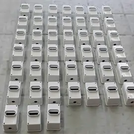 Mehrere weiße, lackierte Metallgehäuse in Reihung auf einem Werkboden.